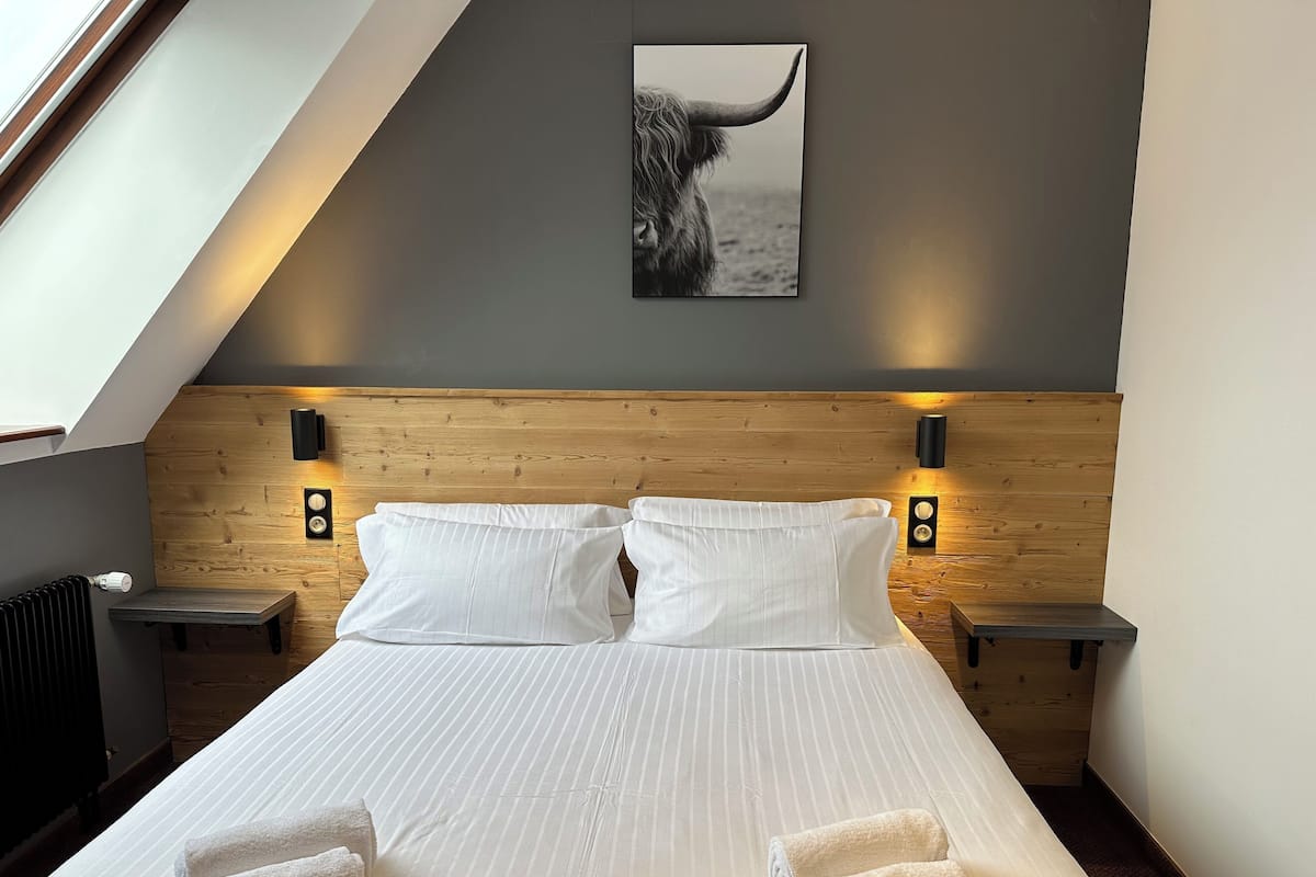 A modern bedroom with a large bed, two bedside tables, and a wooden headboard.