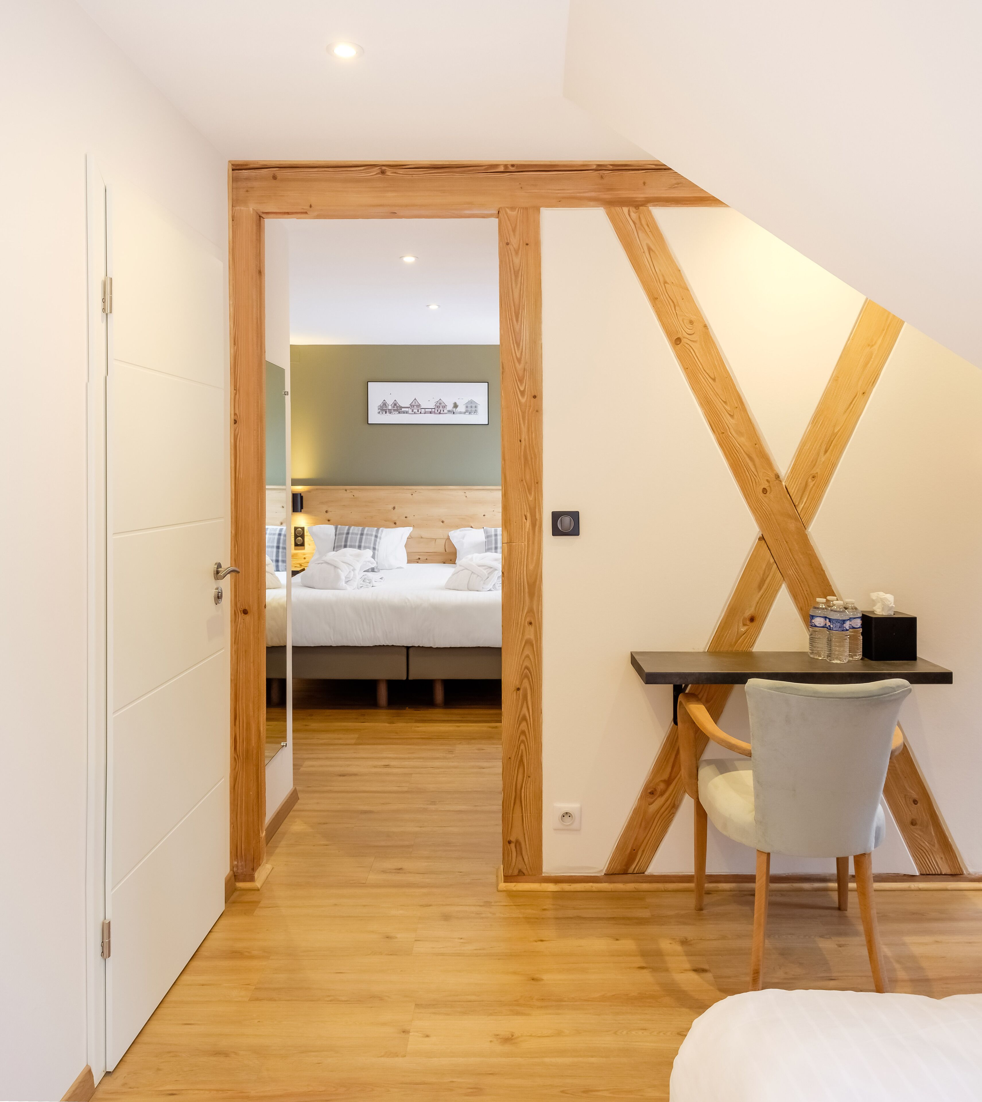 Un dormitorio con techo de madera, una cama, un escritorio con silla y un cuadro en la pared.