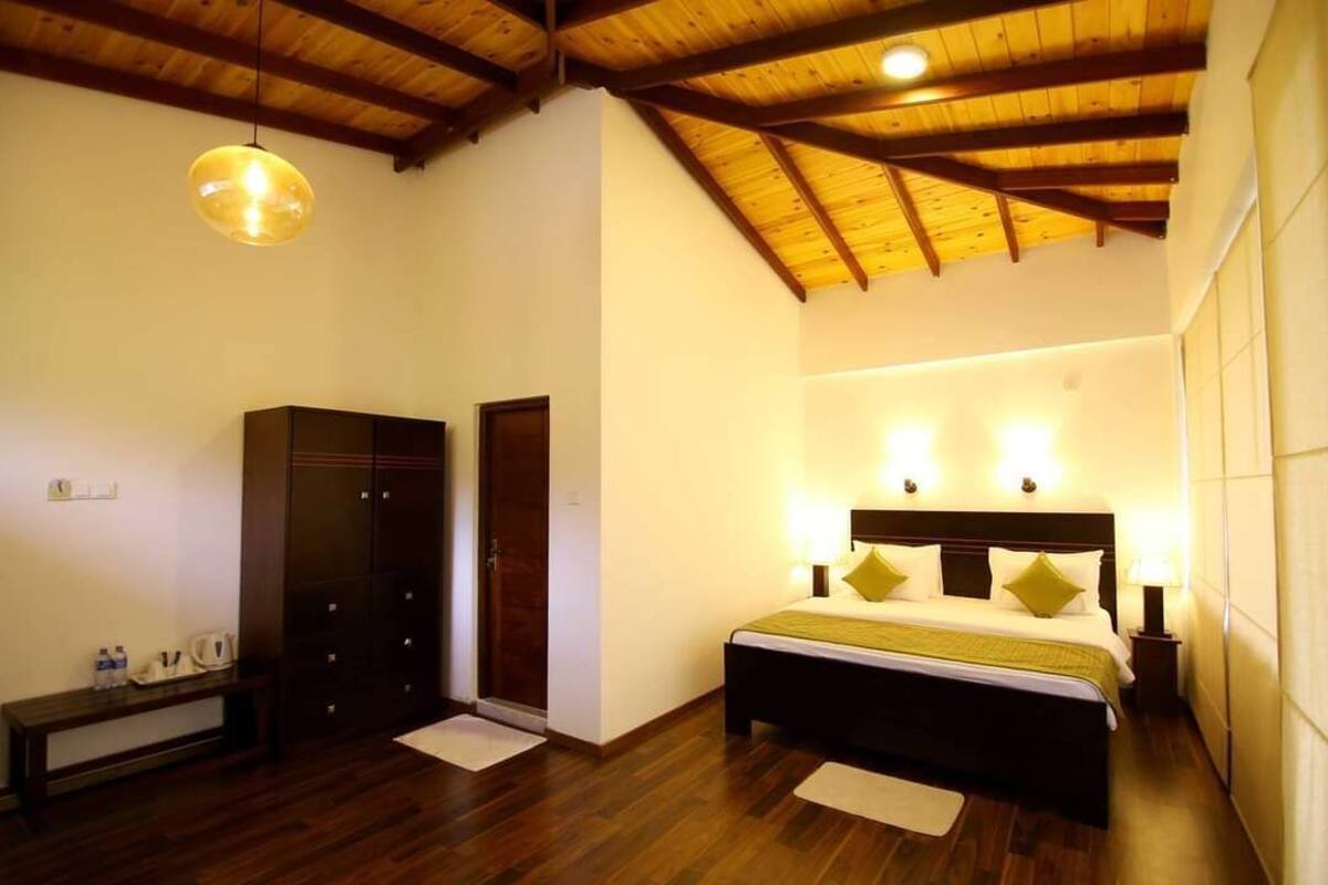 Un dormitorio con techo de madera, una cama con cabecera, lámparas de noche y un armario.