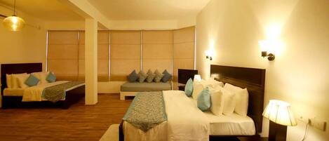 A hotel room with two beds, a sofa, a bedside table with a lamp, and a phone.