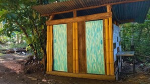 A small wooden structure with a corrugated metal roof, surrounded by dense foliage. - Cabaña el Ermitaño  (Jacó)