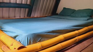 A bed with a blue mattress and green pillows, surrounded by yellow bamboo frames. - Cabaña el Ermitaño  (Jacó)
