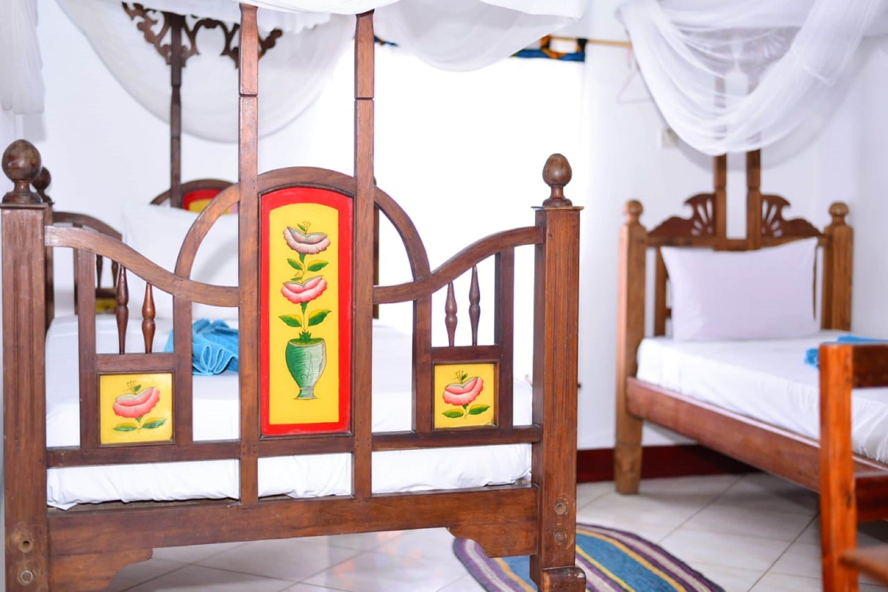 Una cama de madera con dosel, una mesita de noche y un estante en la pared con fotografías enmarcadas.