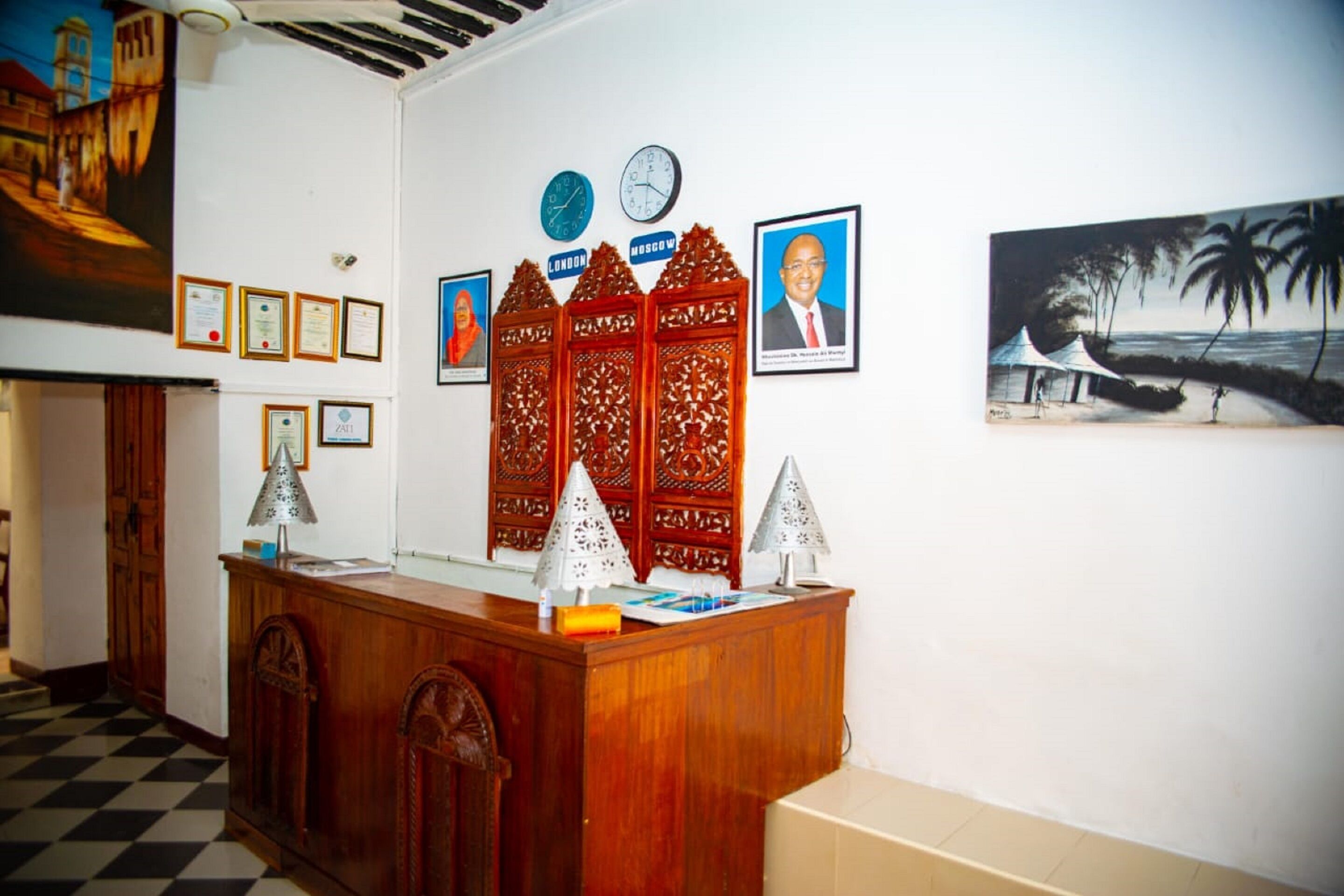 Una recepción con cuadros de certificados, un reloj y una pintura de una playa.