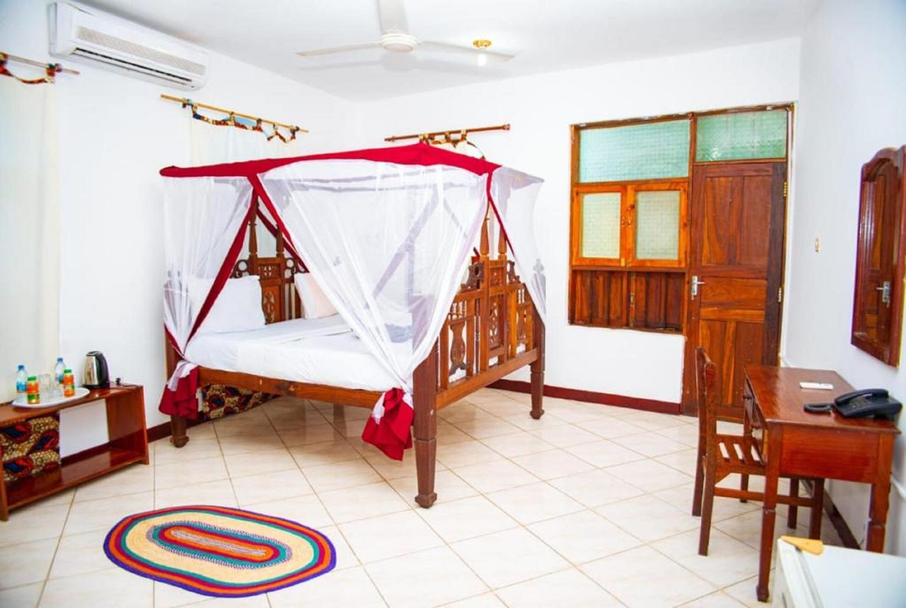 Une chambre à coucher avec un lit en bois, une moustiquaire, un bureau et une chaise.