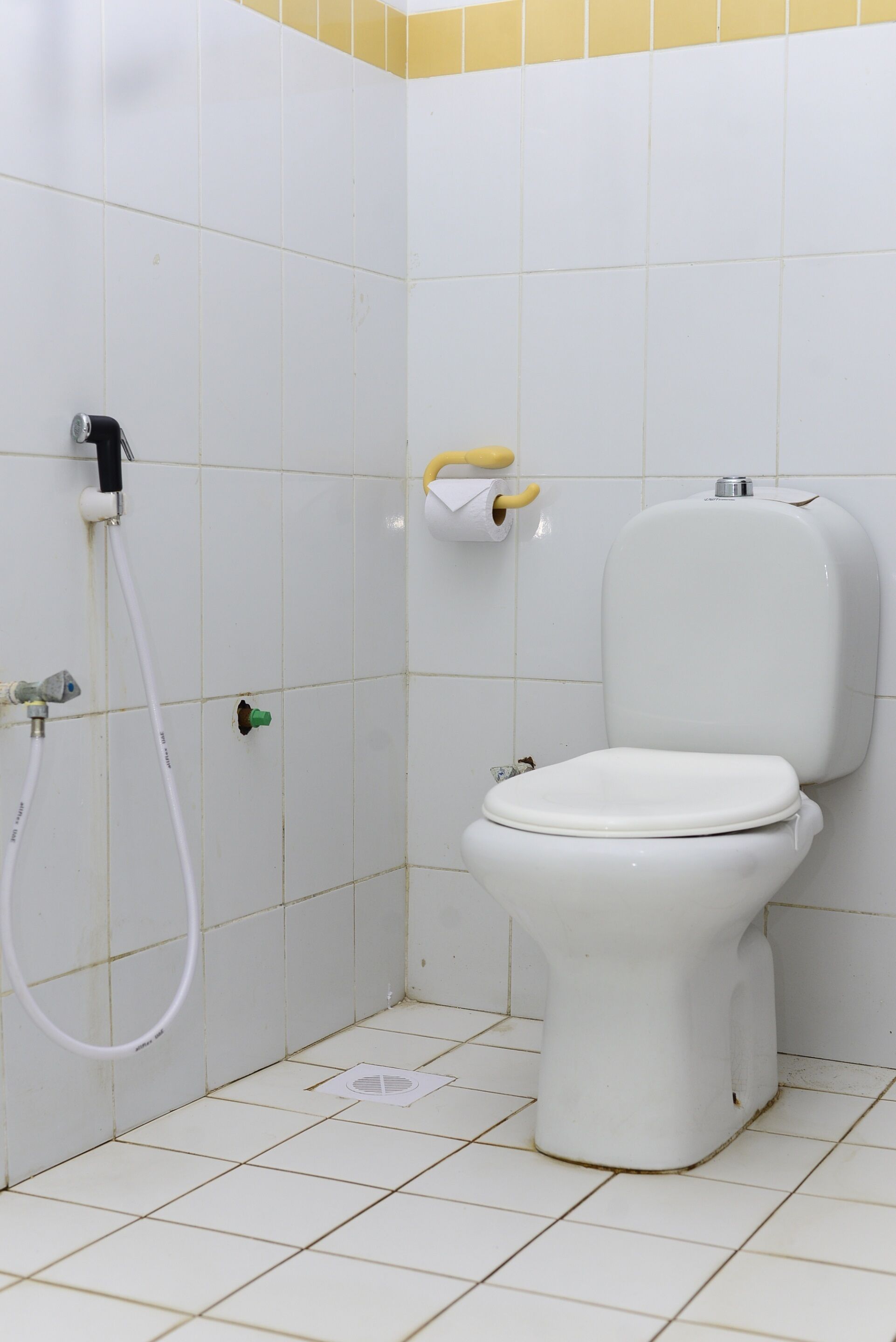 A small, white bathroom with a toilet, a shower, and a towel rack.