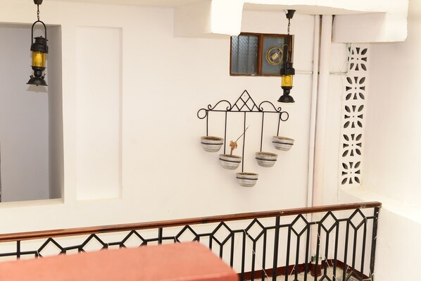 A room with a white wall, a black metal railing, and a window with a decorative metal piece. - La Neisha Hotel Zanzibar (Zanzibar Town)