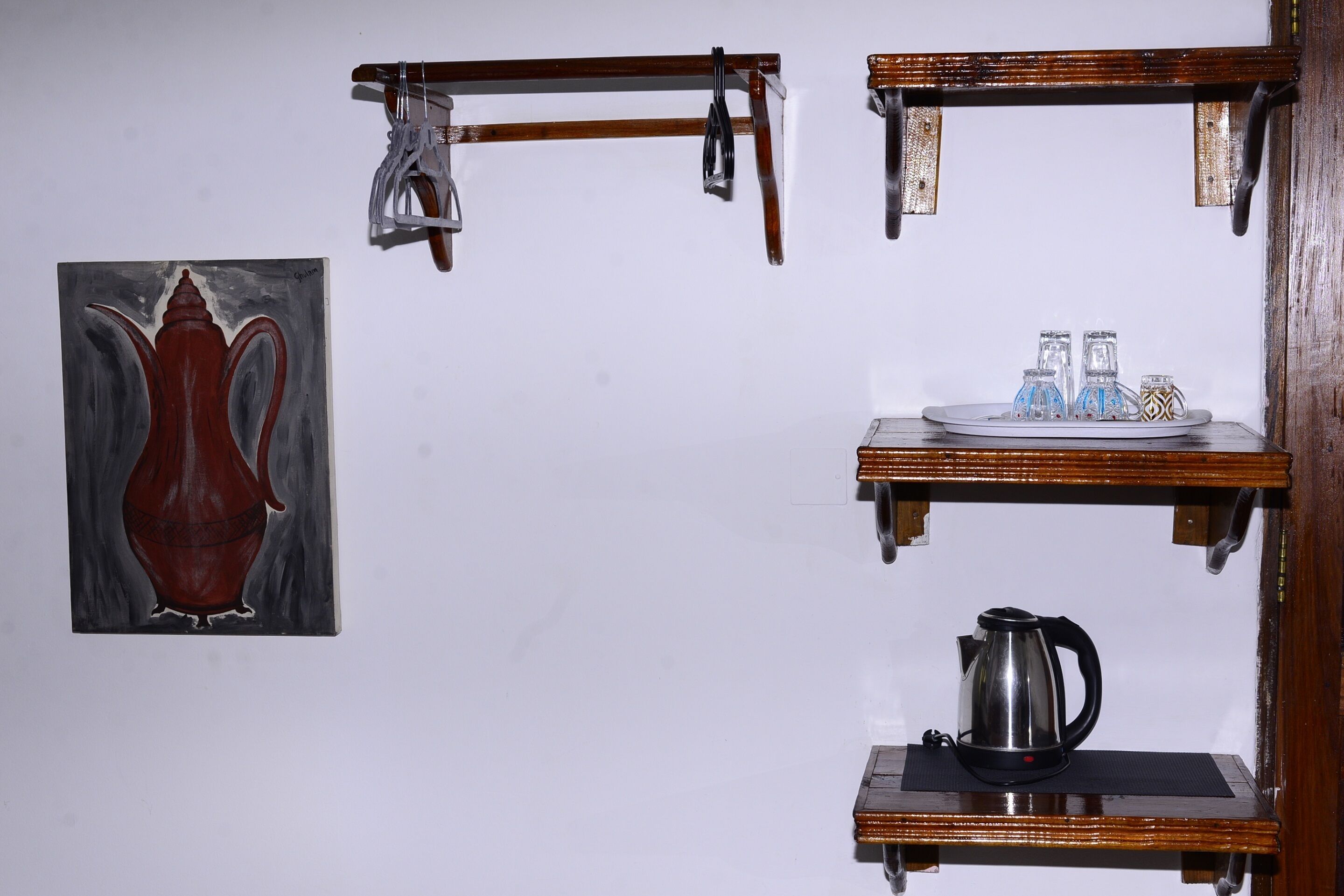 Una cocina con un cuadro, una tetera y una bandeja con vasos.