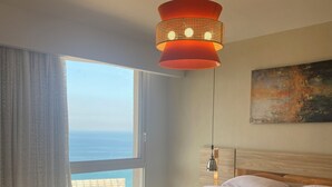 A bedroom with a large bed, a view of the beach, and a modern pendant light. - Sea view il monte galala chalet 3bedroom (Suze)