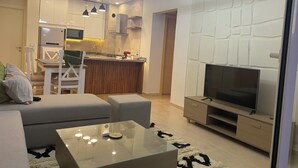 A modern living room with a glass coffee table, a sofa, a TV, and a kitchen area with a microwave and a sink. - Sea view il monte galala chalet 3bedroom (Suze)