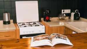 A kitchen with a white stove, a coffee maker, and a kettle on the countertop. - WELCS CASA 089 EMP cerca del mar (Empuriabrava)