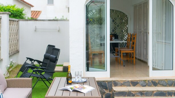 An outdoor patio with a table, chairs, a bottle, and glasses. - WELCS CASA 089 EMP cerca del mar (Empuriabrava)