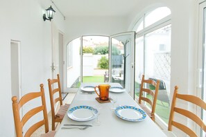 A dining table set with plates, cutlery, and a pitcher, with chairs around it.