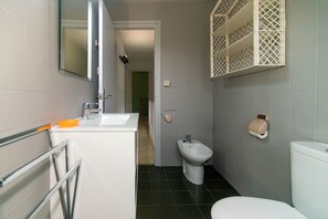A bathroom with a white sink, bidet, and toilet.