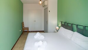 A hotel room with a bed, a chair, a nightstand with a lamp, and an air conditioning unit. - WELCS CASA 089 EMP cerca del mar (Empuriabrava)