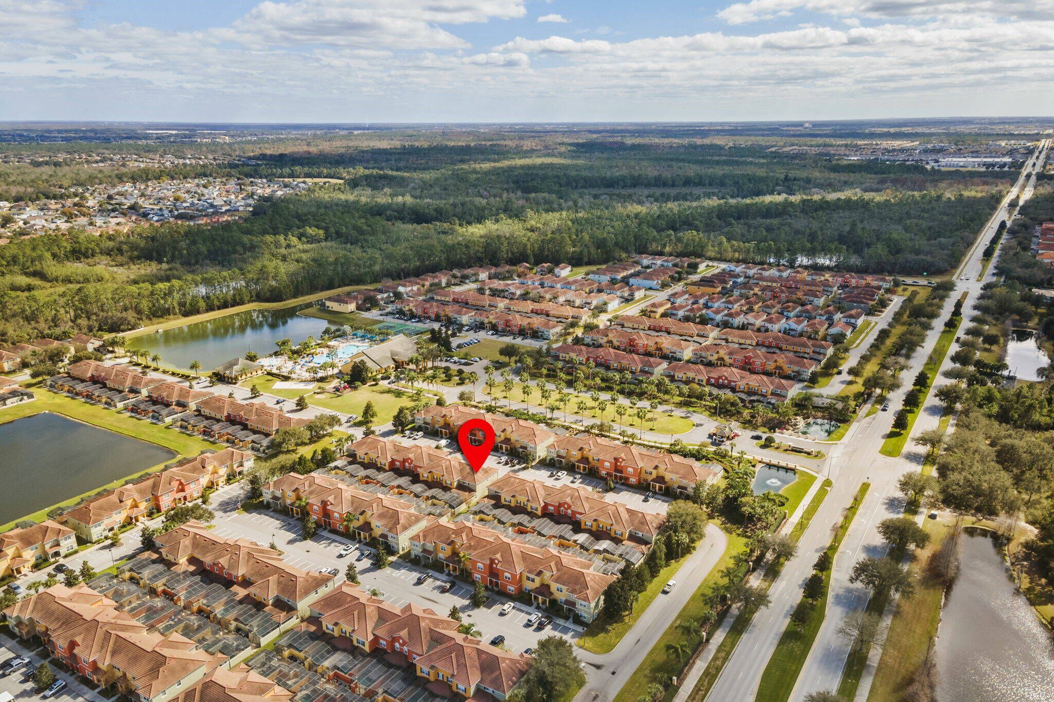 Vista aérea de una zona residencial con varios edificios de apartamentos, un parque central y un lago.