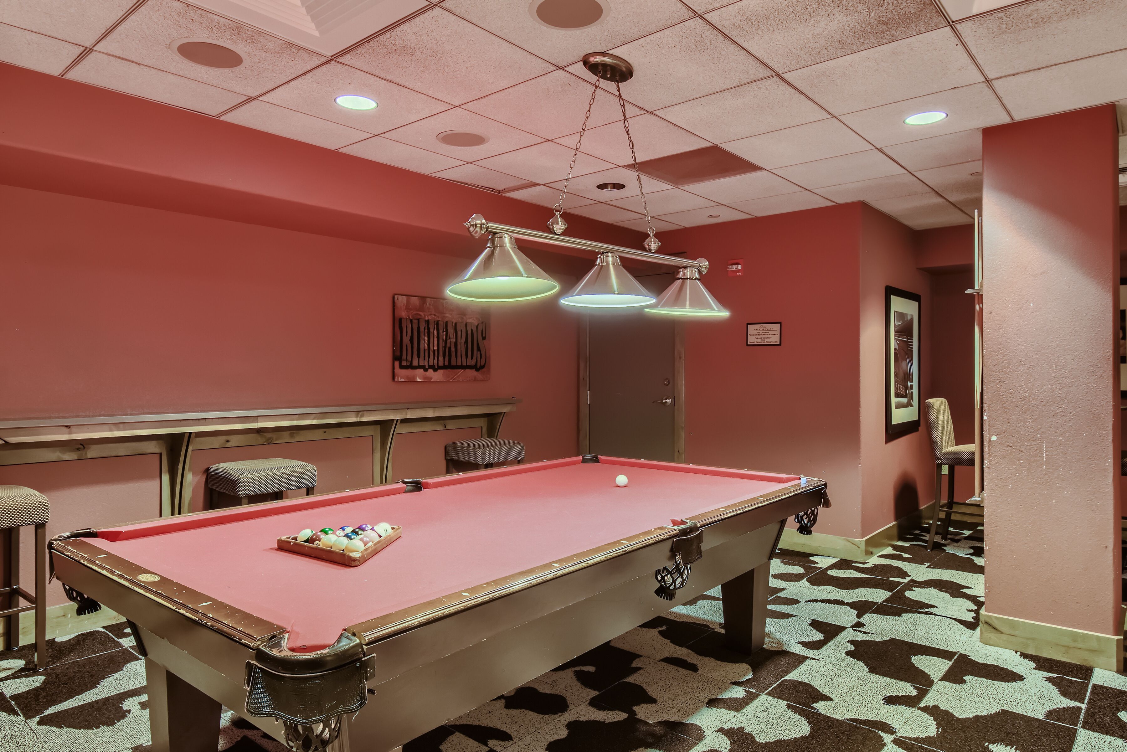 Une table de billard recouverte d’un feutre rouge, un jeu de queues de billard et une bille.