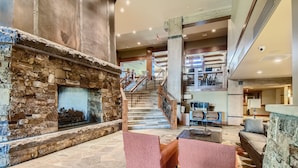 A lobby with a stone fireplace, a staircase, and seating areas.
