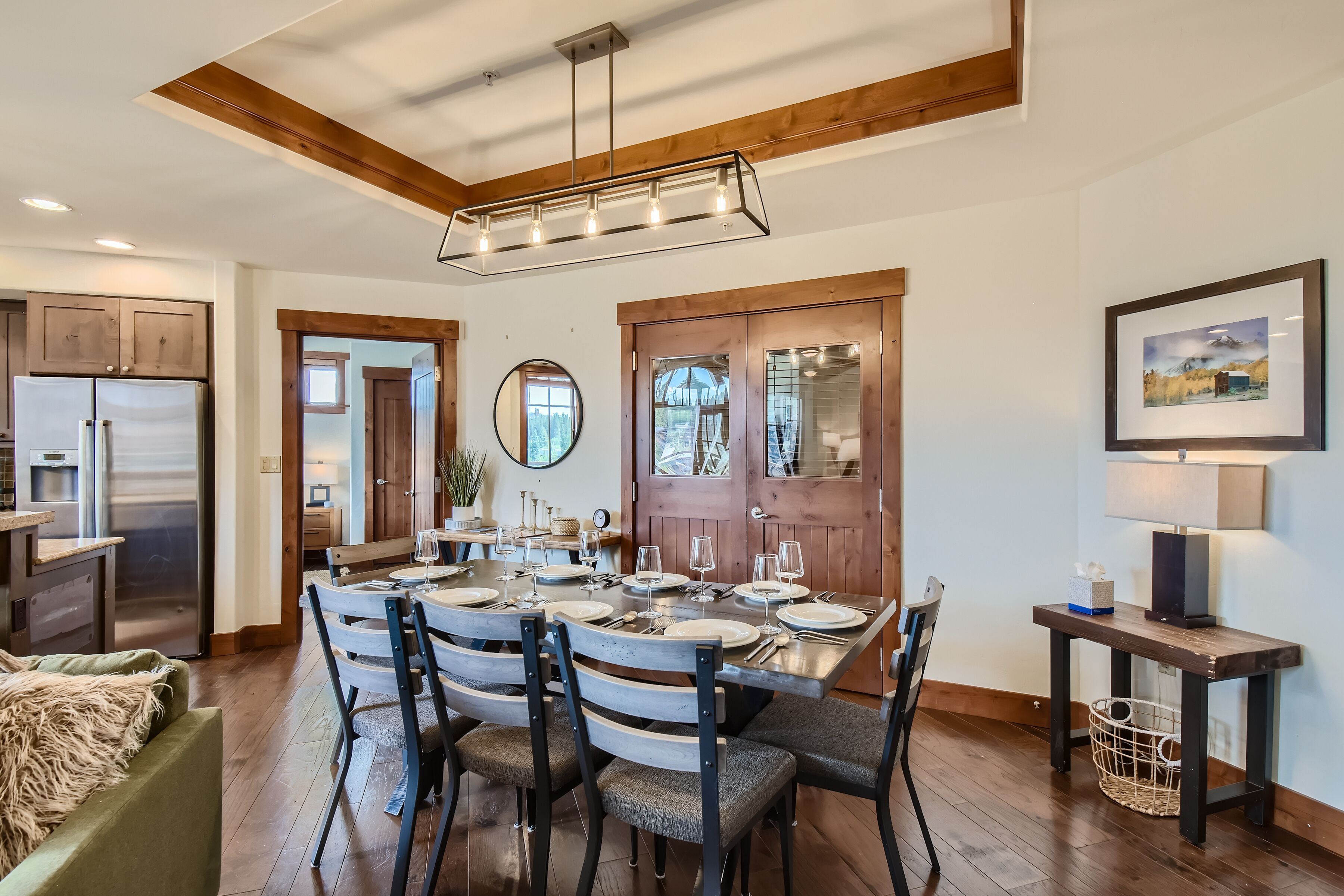 A dining area with a wooden table set for six, surrounded by chairs.