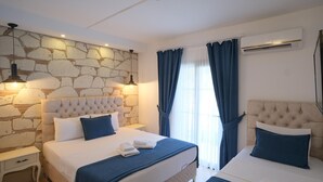 A hotel room with two beds, stone wall, modern lighting, and an air conditioning unit.