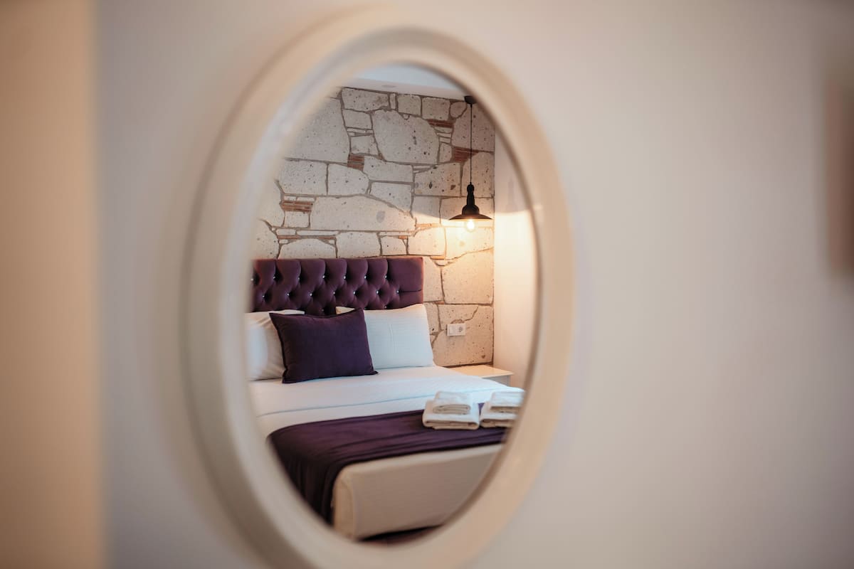 Quarto com parede de pedra, cabeceira estofada e luminária de cabeceira.