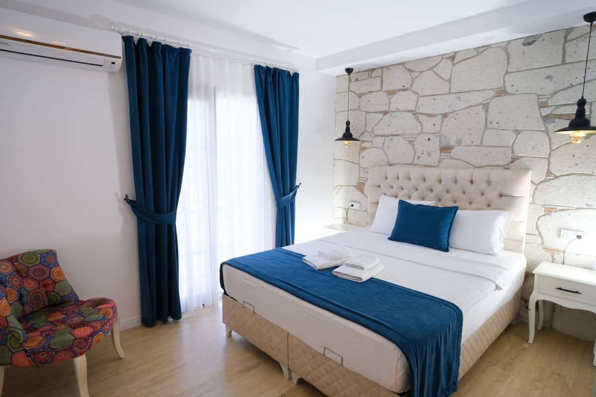 Quarto com uma cama grande, uma cadeira e uma parede de pedra.