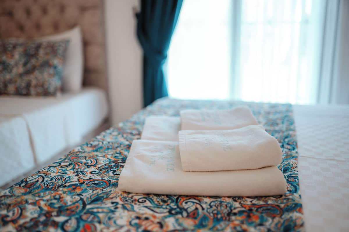 Cama bem arrumada com colcha estampada e toalhas dobradas.