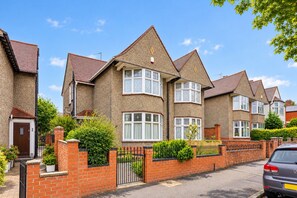 A row of two-story houses with pitched roofs, brick walls, and a gated driveway. - Elegant House • Central Location • Sleeps 8 • Free Parking • Fast Wifi • VirginTV • By Yoko Property (Northampton)