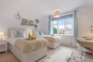 A bedroom with two beds, a desk, a chair, a radiator, and a window with curtains. - Elegant House • Central Location • Sleeps 8 • Free Parking • Fast Wifi • VirginTV • By Yoko Property (Northampton)