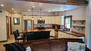 A modern kitchen with white cabinets, stainless steel appliances, and a wooden island.
