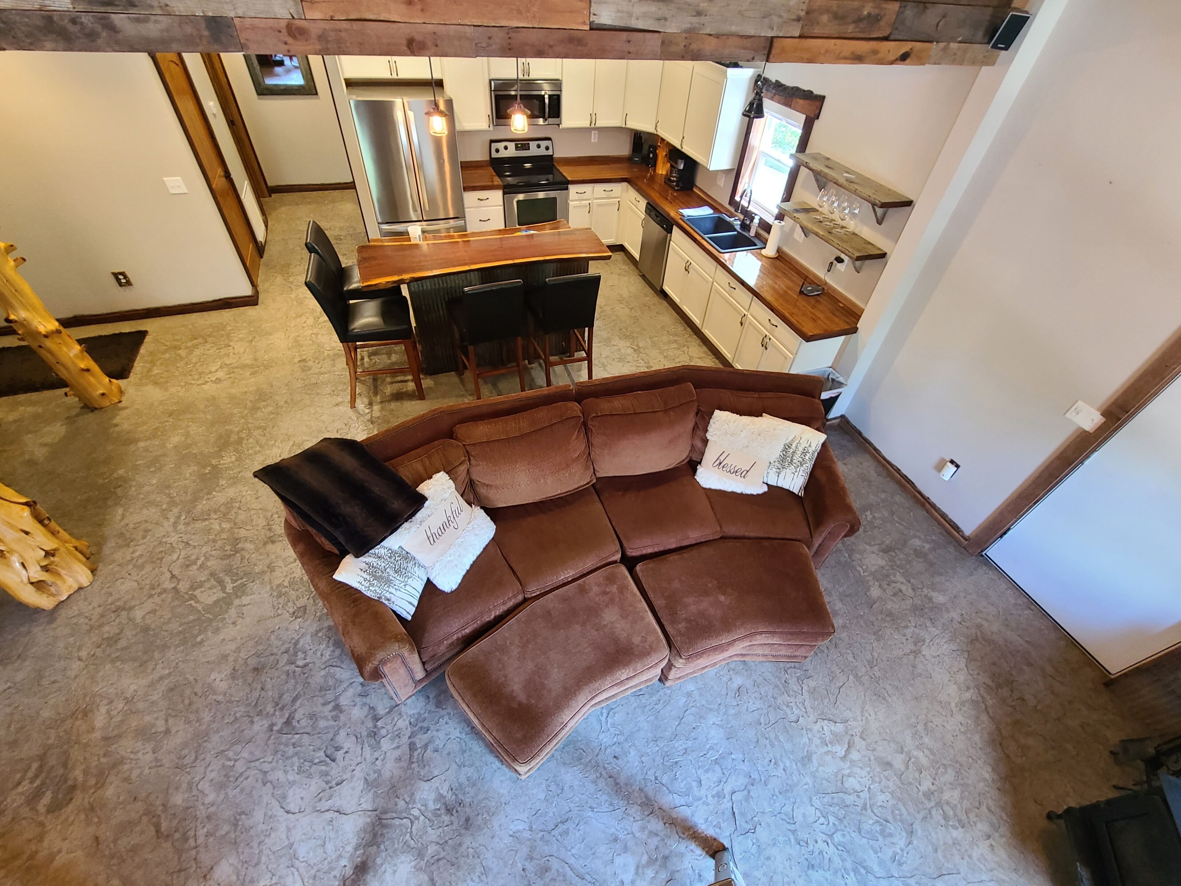 A cozy living room with a brown leather sofa, a wooden coffee table, and a kitchen in the background.