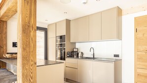 Eine moderne Küche mit hellen Holzschränken, einer Edelstahlspüle und einem eingebauten Backofen.