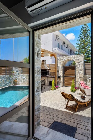 Ein Poolbereich mit Steinmauern, einer Holzpergola und Sitzgelegenheiten im Freien.