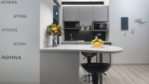 Een moderne keuken met een wit aanrecht, een zwarte spoelbak en een magnetron. Op het aanrecht staat een vaas met bloemen en een schaal met fruit.