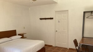 A bedroom with a wooden bed, a small bedside table, a chair, and a door. - POSADA CAMPESTRE XICOTEPEC (Xicotepec)