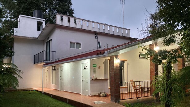 A two-story house with a covered porch, a small balcony, and a brick column. - POSADA CAMPESTRE XICOTEPEC (Xicotepec)