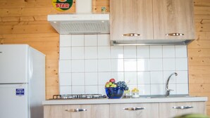 Una cocina con armarios de madera, salpicadero de azulejos blancos, un lavamanos y un bol con fruta en la encimera.