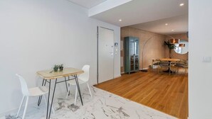 A modern living room with a wooden floor, a dining area with a table and chairs, and a built-in wardrobe. - Vita Luxus (Setúbal)