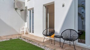 A patio with a small lawn, two black chairs, and a white chair. - Vita Luxus (Setúbal)