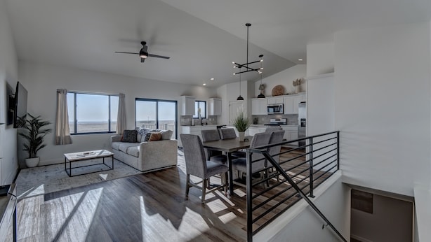 A spacious living area with a dining table, sofa, and a staircase leading to an upper level. - Luxury Rapid City Home #1 (Rapid City)