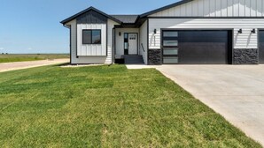 A modern two-story house with a garage, a well-maintained lawn, and a clear sky. - Luxury Rapid City Home #1 (Rapid City)