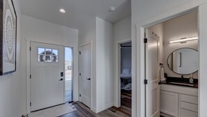 A hallway with wooden flooring, white walls, and a door leading to a bedroom. - Luxury Rapid City Home #1 (Rapid City)