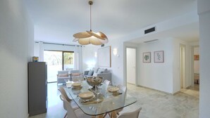 A modern dining area with a glass table, white chairs, and a unique pendant light.
