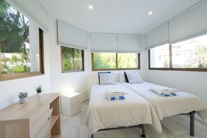 A hotel room with two beds, a desk, and a window with blinds. - 2035 Modern Family Apartment on Golden Beach (Marbella)