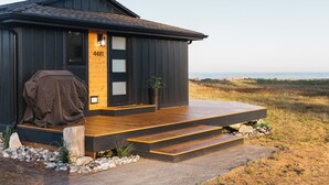 A modern house with a wooden deck and a view of the beach. - Lux Coastal Retreat & Hot Tub (Oak Harbor)