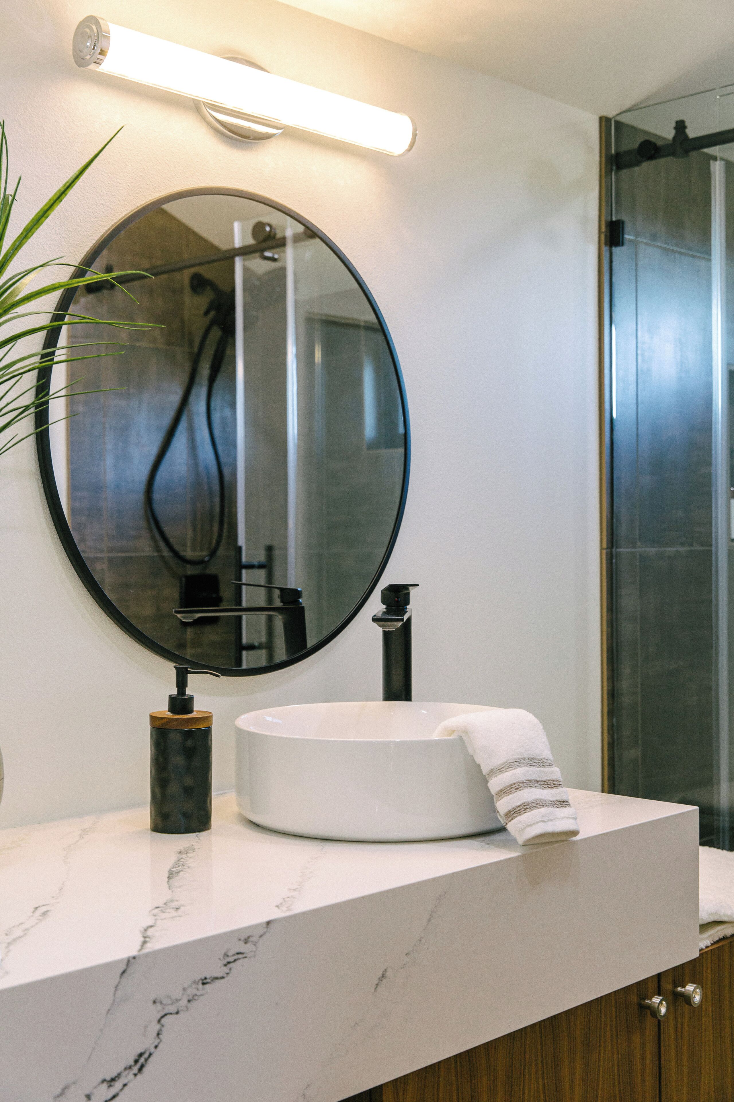 A bathroom with a round mirror, a white sink, and a towel.