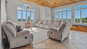 A spacious living room with a high ceiling, large windows, and a view of the outdoors. - Willow Brook Mansion, an upscale retreat in the countryside with heated seasonal (May 1st - Oct. 1st) pool, hot tub and game room. (Millerstown)