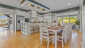 A spacious kitchen with white cabinetry, a central island, and a dining area with white chairs. - Willow Brook Mansion, an upscale retreat in the countryside with heated seasonal (May 1st - Oct. 1st) pool, hot tub and game room. (Millerstown)