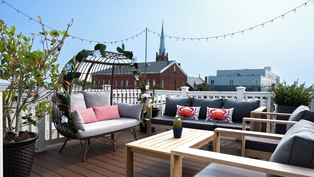 A rooftop deck with outdoor furniture, a potted plant, and a view of a church steeple. - Spacious Fed Hill Home w/Rooftop & 4 Parking Spots (Baltimore)