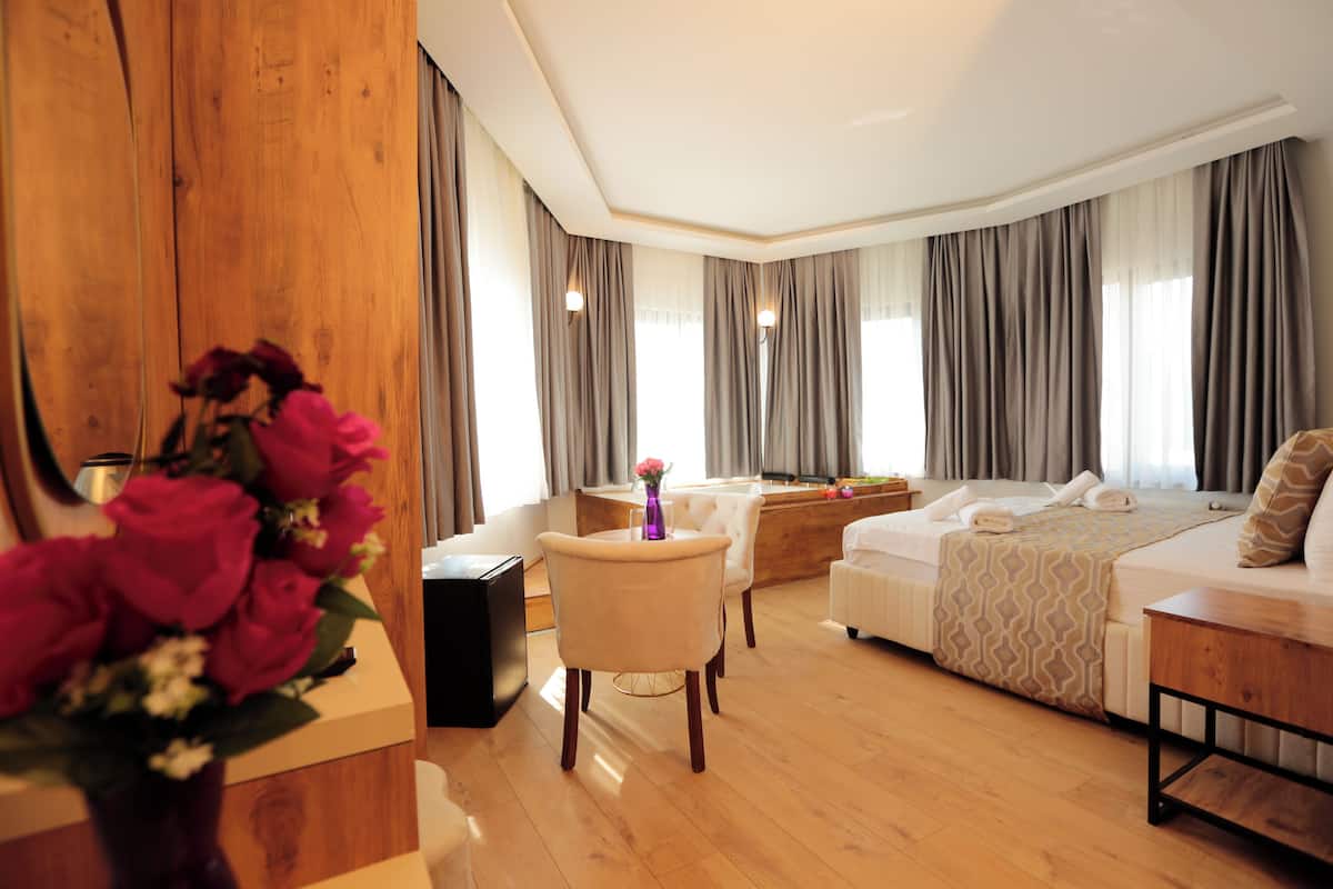 A hotel room with a bed, a desk, a chair, and a wooden accent wall.